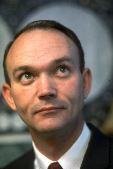 A formal portrait of Michael Collins wearing a suit and tie.